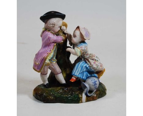 An early 20th century bisque porcelain figure group of young boy and girl, each in period costume and kneeling against a tree