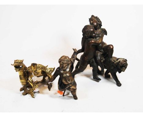 A Chinese brass candlestick, in the form of a dragon, height 13cm, together with a bronze figure group of two putti and a lio