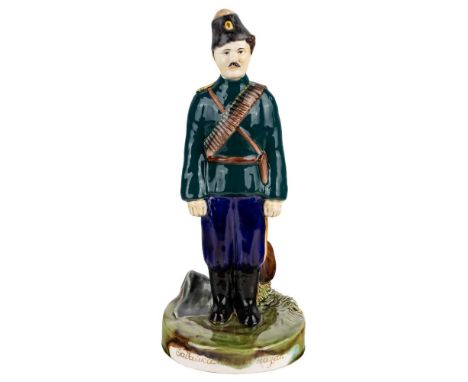 A RUSSIAN PORCELAIN FIGURE OF A TRANSBAIKALIAN COSSACK, KUZNETSOV PORCELAIN FACTORY realistically modelled in a teal green un