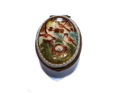 An 18th century south Staffordshire enamel oval patch box, blue ground and the cover painted with birds perched in a tree and