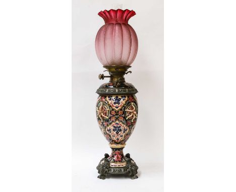 A Zsolnay pottery oil lamp with brass mounts, chimney and pink glass shade, and an Oriental carved hardwood figural lamp base