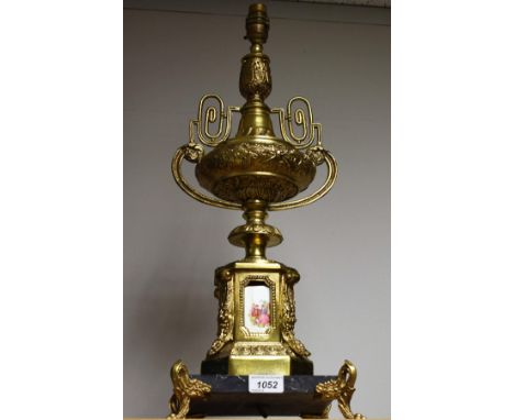 A Continental gilt metal table lamp, the stem modelled as a two handled urn on plinth inset with ceramic panels decorated wit