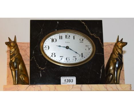 An Art Deco style marble mantel timepiece, mounted with a pair of stylised spelter seated hounds, oval dial with Arabic numer