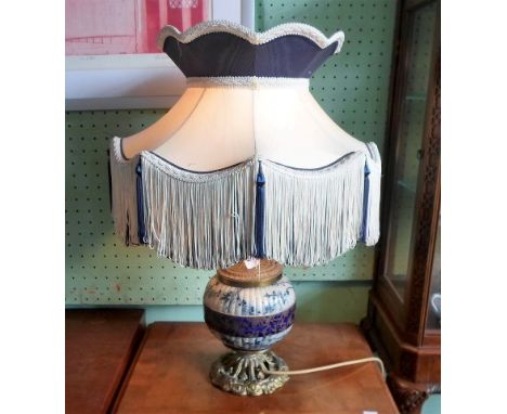 A late Victorian ceramic and gilt metal table lamp in the aesthetic manner, with tassled shade, 58cm.