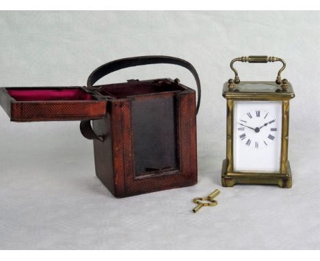 An early 20th century gilt brass mantle clock, the enamel dial bearing Roman numerals, in a fitted red leather travel case, t