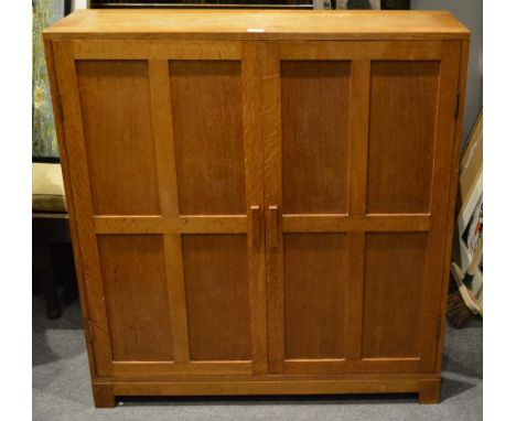 A Cotswold style oak cupboard in the manner of Heals circa 1920, with panelled doors enclosing shelves, on bracket feet, 108c