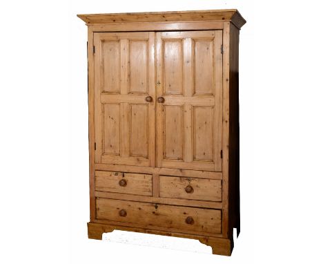 A Victorian pine cupboard with two panelled doors over two short and one long drawer, all with turned handles, standing on br