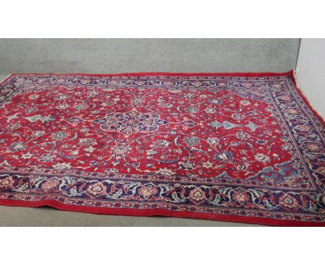 A handmade Persian Keshan carpet with central foliate medallion on a burgundy ground within foliate multiple borders. L.350 W