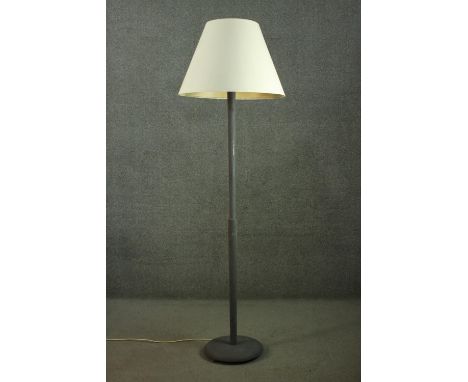 An ebonised standard lamp, with a cream shade, on a cylindrical stem, with a circular base. H.185cm. 
