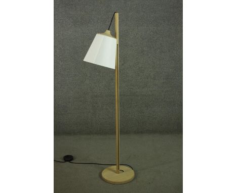 A contemporary light oak standard lamp, the white shade hanging from a cylindrical stem, on a circular base. H.152cm. 