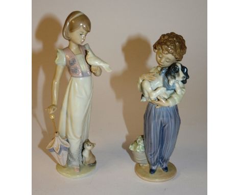 Two Lladro figures, in the form of a boy holding puppy, and a girl with dove and kitten, holding a parasol, 24cm high (2)