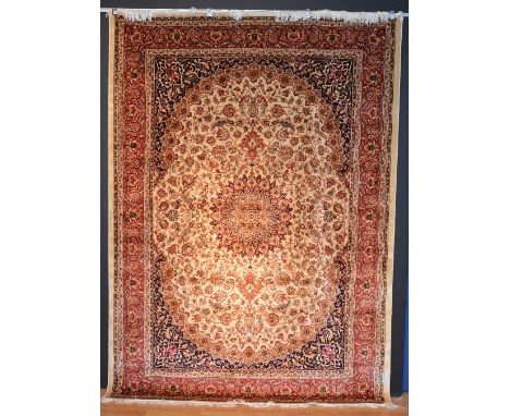 A machine made Keshan carpet, decorated with central floral motif on beige floral ground, with red and blue floral border, 28