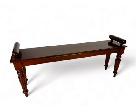 A Regency mahogany bench in the manner of Gillows
The rectangular moulded seat with paper scroll arms; on turned fluted legs 