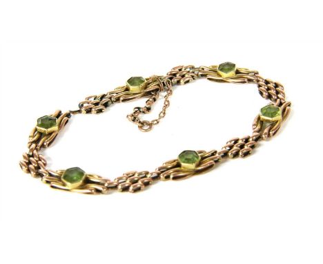 An Edwardian gold peridot gate bracelet, with an octagonal step cut peridot rub set to the centre of each gate link, to conce