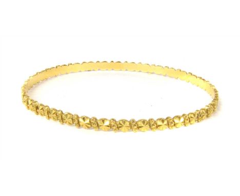 A high carat gold flat section slave bangle, with diamond cut circular decoration between beaded diagonal lines, 14.63g