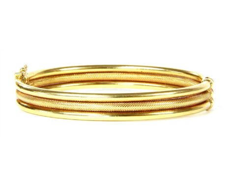 An Italian gold three row bangle, hinged oval bangle with three rows of round section wire, the central row with dimpled deco