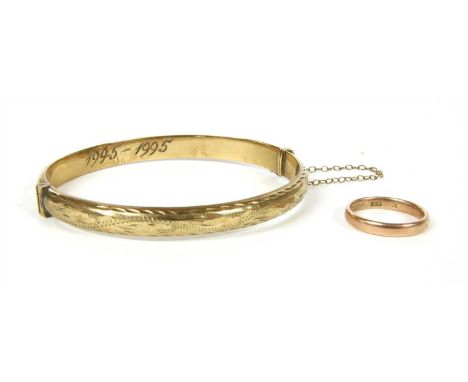 A 9ct gold hollow D section hinged bangle, the top half with engraved foliate decoration to plain polished bottom half, hand 