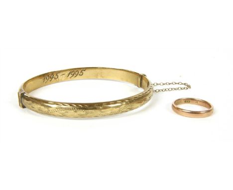 A 9ct gold hollow D section hinged bangle, the top half with engraved foliate decoration to plain polished bottom half, hand 