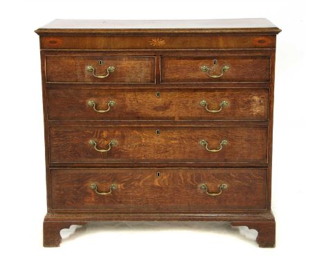 A George III oak chest of two short over three long graduated drawers, with shell inlay on bracket feet