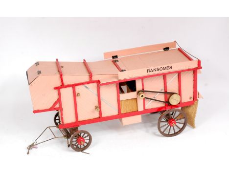 A freelance wooden and brass constructed model of an approximately 1" scale threshing machine, finished in pink and red with 