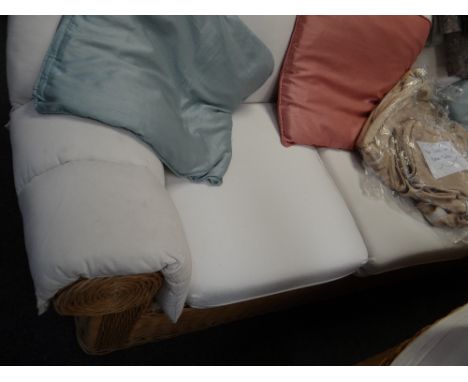 A three-seater rattan rolled arm & back sofa with loose covers