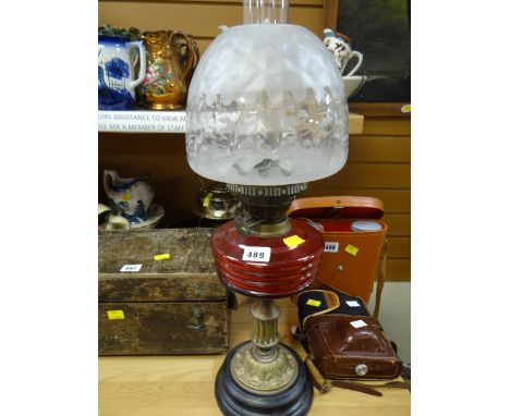 A vintage oil lamp with red glass reservoir