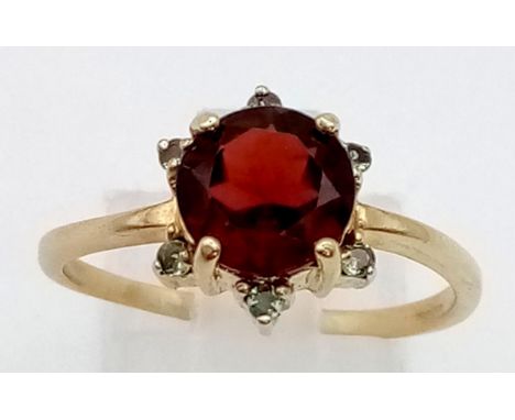 A 9K Yellow Gold Red and Green Garnet Ring. Large central red garnet with a halo of small green garnets.Size T. 2.93g total w