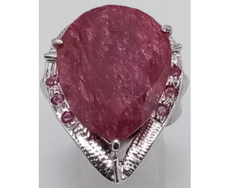 A sterling silver ring with a large pear cut ruby surrounded by a silver halo with nine small rubies. Ring size: P, weight: 2