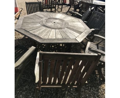 An octagonal teak garden table, 150 cm long x 150 cm deep x 70 cm high, together with six folding chairs and a small bench
