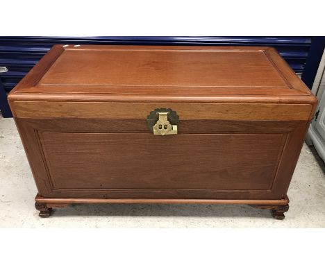 A Chinese cherry wood trunk with fielded panels opening to reveal a lined interior on carved squat cabriole supports to scrol