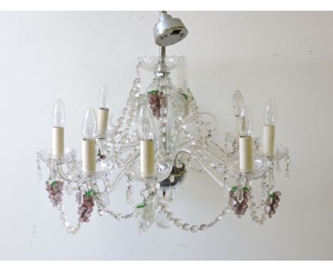 A contemporary glass chandelier, with scrolled branches, glass drops, and bunches of grapes