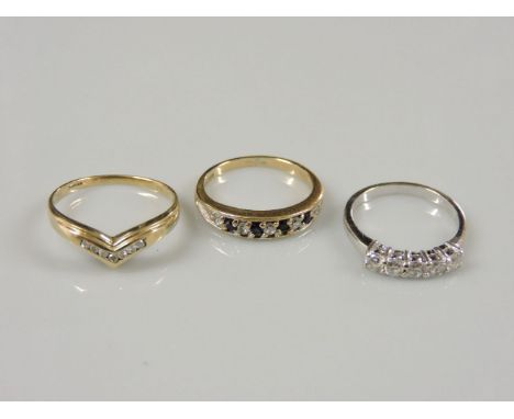 A 9ct gold diamond set wishbone ring, size P½, a 9ct white gold five stone cubic zirconia ring, size K½, and a 9ct gold sapph