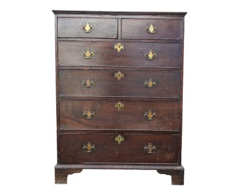 A George III oak chest of drawers - with an arrangement of two short and four long graduated drawers incorporating a brushing