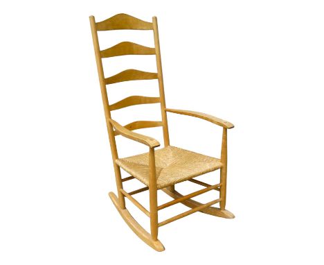 A 20th century ash Cotswold School ladder back rocking chair - in the manner of Philip Clisset, with a rush seat.