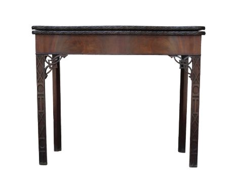 A George III mahogany card table - with serpentine top, the edge with strapwork carving, the square legs with blind fretwork,