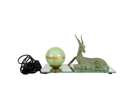 An Art Deco table lamp - with a recumbent antelope and green globe light, on a rectangular mirrored base, 35cm wide.