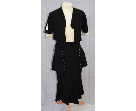 A BLACK SKIRT AND MATCHING JACKET, the skirt with overlaid black panel, decorated with cream and black side buttons, the jack