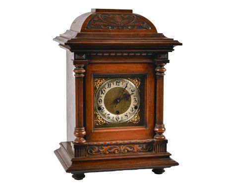 A German walnut basket-top mantel clock, c1900, the movement chiming on rod gongs, brass and silvered dial, pendulum and key,