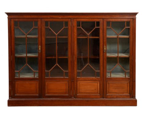 An Edwardian mahogany bookcase, fitted with adjustable shelves enclosed by four glazed doors, the lower part each panelled, f