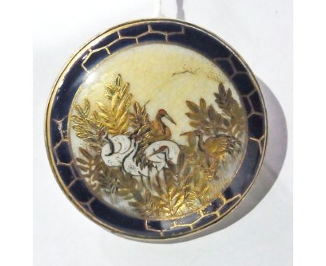 Japanese satsuma pottery brooch mounted in gold coloured metal, blue border having raised gilt and enamel decoration of crane