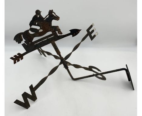 A wrought iron weather vane showing a horse and rider 