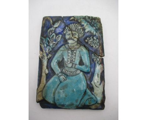 An antique Islamic moulded tile depicting a kneeing man, approx. 17cm x 12cm - A/F