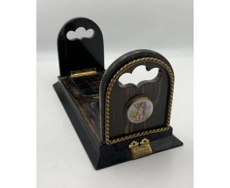 A 19th century Rosewood and brass mounted fold away Bookstand with ceramic plaques mounted depicting cherubs: Patent Betjeman