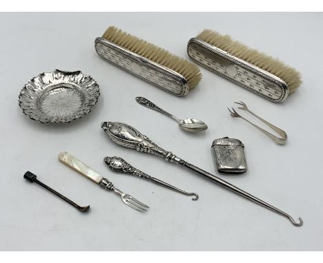 A collection of hallmarked silver items including a dish, brushes, silver handled button hooks etc.