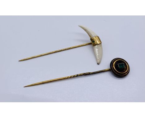 Two yellow metal stick pins, one set with an emerald