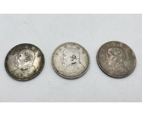 Three Chinese silver dollars, two Fat Man (Yuan Shih-Kai) dollars and one junk dollar.