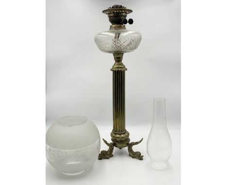 A Victorian brass oil lamp on column base with stylised dolphin feet and frosted shade