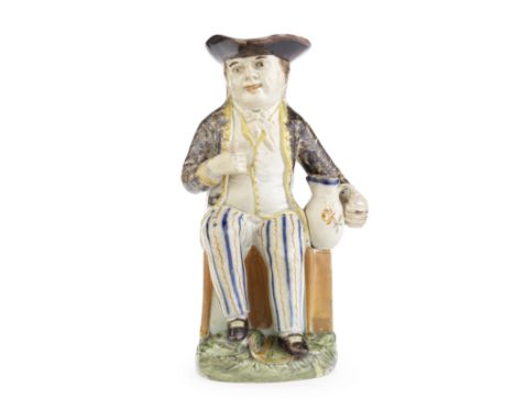 A rare Prattware 'Sailor' Toby Jug, circa 1795-1800Seated on a high-backed chair above a sea chest, an anchor between his fee