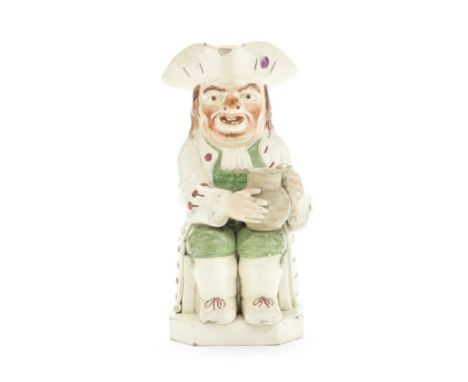 A creamware 'Ruddy-Faced' Toby Jug, circa 1810-20Of traditional form, grasping a well-potted jug in both hands, a pipe leanin