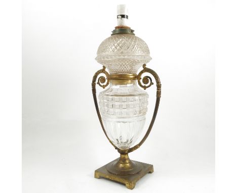 A 19th century gilt metal and cut glass oil lamp base, converted to electricity, of urn form, with scroll handles, raised on 